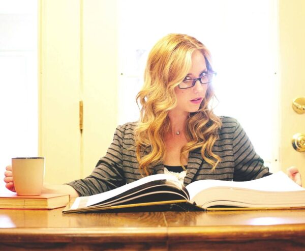 mulher loira com óculos um livro em cima da mesa